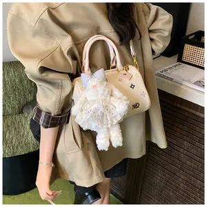Chic cream Boston bag with colorful pattern and cute plush bunny charm shown on model