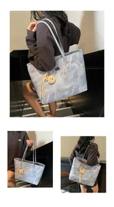 Detail showing marble texture blue tote bag with plush bear charm and brand logo