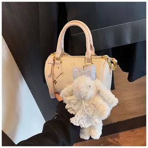 Close-up of cream Boston bag with gold star patterns and a large plush rabbit charm