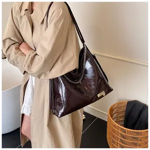 Detailed close-up of dark brown oil wax leather tote bag with silver chain accessory