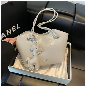 Detail einer cremefarbenen Leder-Tote-Bag mit dekorativem Giraffen-Anhänger und Markenlogo