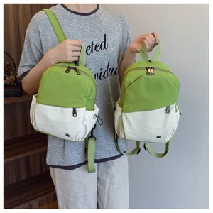Detalle de la mochila de nailon verde y beige con cremalleras dobles y bolsillos laterales