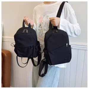 Comparación de tamaños de dos mochilas de nailon negro con diseño minimalista