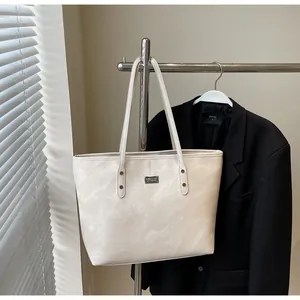 Detail of white large capacity tote bag with leather texture and silver metal plate