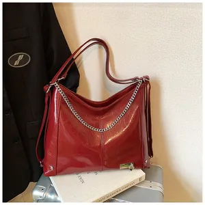 Detail of red oil wax leather tote with silver chain and heart pendant accessory