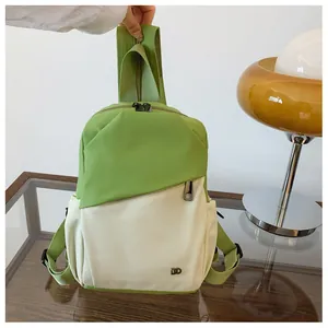 Detalle de la mochila verde y beige con logotipo metálico y bolsillos con cremallera