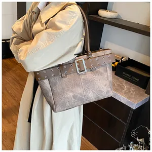 Detail der großen Vintage-Tasche mit braunem Ledergürtel und Metallösen am Rand