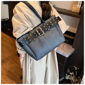 Details einer schwarzen Tragetasche mit Metallschnalle und weißen Kontrastnähten aus Leder
