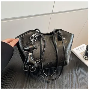 Detail der schwarzen glänzenden Falten-Tote-Bag mit einem süßen Hund-Anhänger als Accessoire