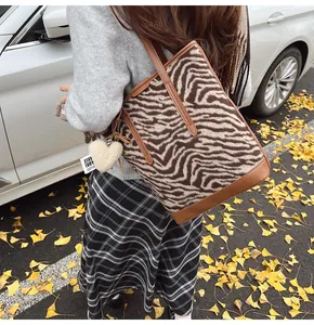 Detail of zebra pattern bucket bag with brown leather straps and plush heart charm