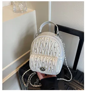 Detail of pearl white quilted backpack with shimmering rhinestones and chain strap