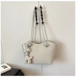 Detail der minimalistischen cremefarbenen Tragetasche mit Leder-Giraffenanhänger