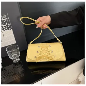 Detail shot of bright yellow PU leather bag with unique cross-tie design and silver buckles
