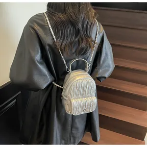 Detail of silver pleated quilted mini backpack with metal chain straps and clasp