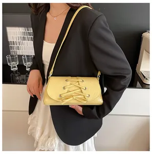 Close-up of bright yellow shoulder bag featuring corset-style lace-up detailing and texture