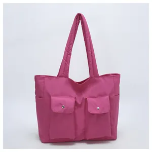 Detail of rose red nylon tote bag featuring dual front pockets with silver snap buttons