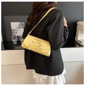 Detail of pale yellow crossbody bag with ribbon bow and lychee texture on black suit