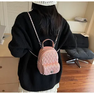 Detail of pink quilted backpack with rhinestone studs and metal woven chain straps