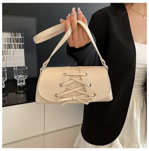 Detail of beige faux leather handbag featuring decorative cross-lacing and metal eyelets
