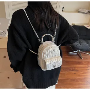 Quilted mini backpack in off-white with rhinestone accents shown on a model