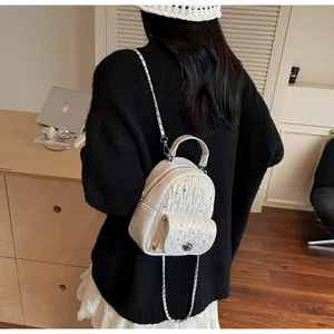 Detailed close-up of white quilted mini backpack with rhinestone studs and silver chain