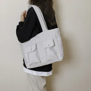 Large light grey nylon tote bag with dual front pockets shown on model for daily style