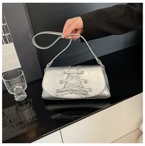 Detailed view of silver metallic bow bag with lace-up corset design and pleated texture
