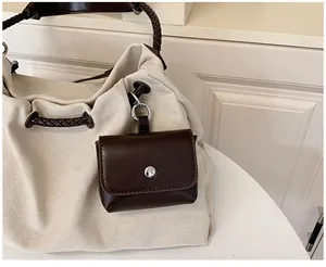 Detail of small brown leather pouch with silver snap button on a cream canvas tote bag