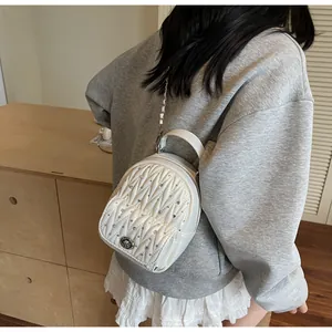Detail of white mini quilted backpack with sparkling rhinestones and metal chain strap
