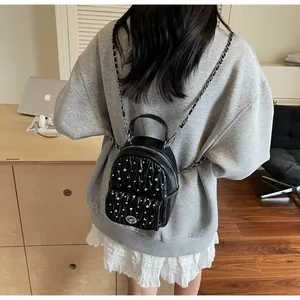 Close-up of black quilted backpack with silver studs and chain straps on model