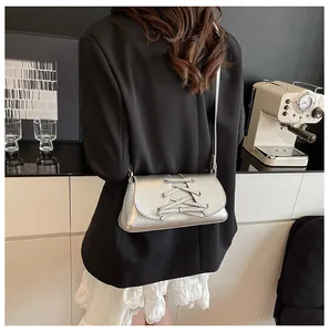 Silver crossbody bag with bow strap detail shown on model in stylish modern outfit