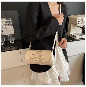 Detail of cream crossbody bag featuring a lace-up corset design and bow accent