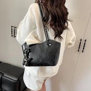 Minimalistische schwarze glänzende Tote Bag mit Faltenstruktur und Bärenanhänger