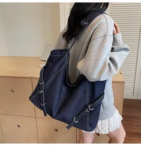 Detail of dark blue denim tote bag with white contrast stitching and silver D-rings