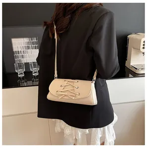 Detail of cream bow crossbody bag with corset lacing on elegant soft leather texture