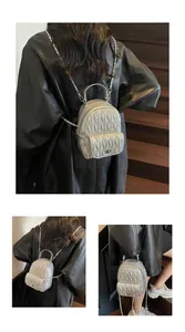 Detail of silver quilted mini backpack featuring metallic ripple texture and chain strap