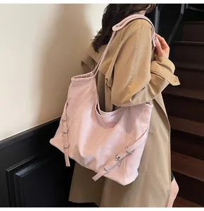 Side view of light pink large capacity tote bag with decorative buckle on light beige stairs