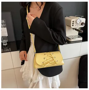 Detail of yellow corset-style crossbody bag with unique lacing and metallic eyelets