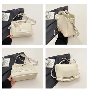 Detailansichten der beigen Leder-Beuteltasche mit Perlenanhänger und Webgriff