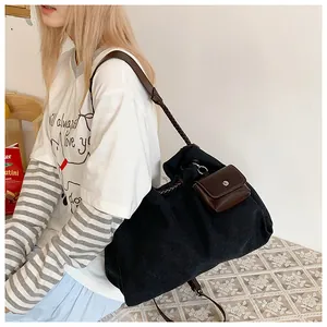Detail of black canvas tote bag with brown braided leather strap and mini pouch charm