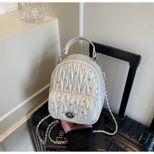 Detail of white quilted backpack with rhinestones and silver chain on black suitcase