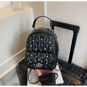 Detailed view of black quilted backpack with silver rhinestones and metal twist lock detail
