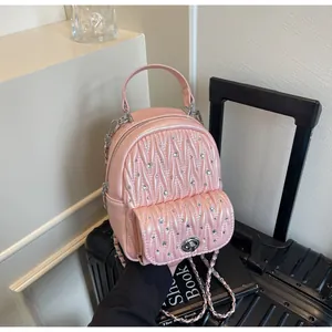 Macro detail of pink quilted mini backpack with sparkling crystals and silver chain strap