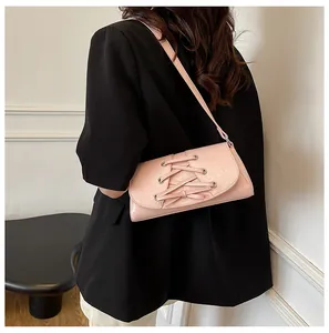 Detail of pink bow-tied crossbody bag showing metallic eyelets and leather texture