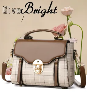 Close-up of vintage plaid crossbody bag with brown leather flap and golden metal lock