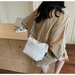 Dettaglio della borsa a tracolla beige in nylon minimalista con tessuto effetto stropicciato