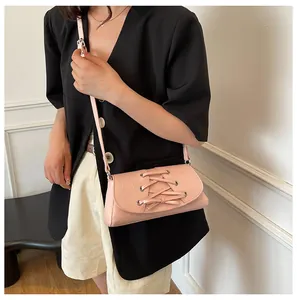 Close-up of pink crossbody bag featuring decorative lace-up detail and metal eyelets