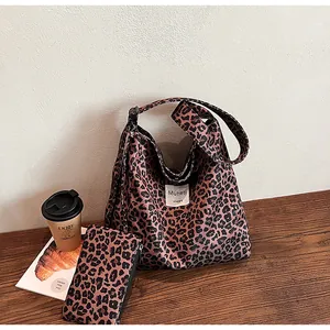 Detail view of large leopard print tote bag with matching pouch on a wooden cafe table