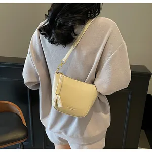 Nahaufnahme der cremeweißen Beuteltasche mit Kiesellederstruktur und goldener Hardware