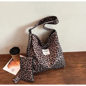 Macro shot of large leopard print tote bag with small zipper pouch on wooden surface